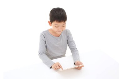 Beyaz arkaplanda izole edilmiş tablet bilgisayar kullanan Asyalı çocuk.