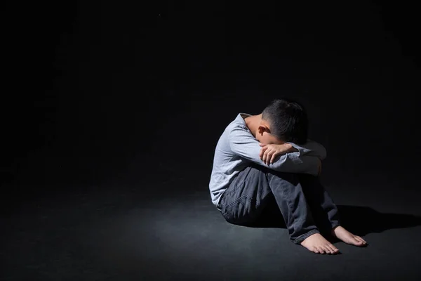 Asya 'lı Çocuk Kara Arkaplan' da dizlerinin üstüne çöküp oturuyor. Konsept: depresyonda. Hayal kırıklığına uğradım. Duygu. 