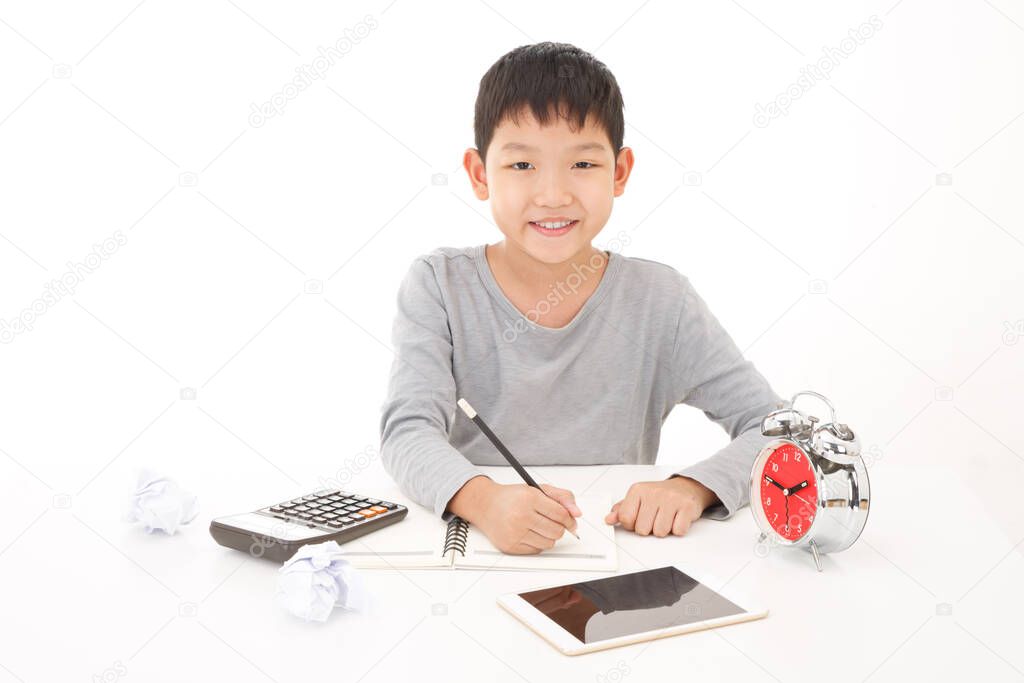 Little asian boy use pencil writing on notebook with smiling face on white background. Planing Education Concept.
