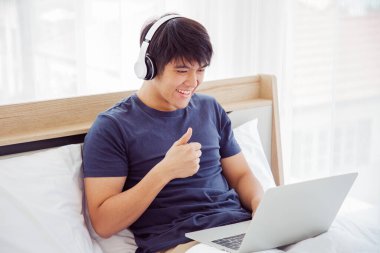 Yatak odasındaki bilgisayar görüntülerini kullanırken mutlu adam Thunb harekete geçti. Kopyalama uzayı. Ticaret, Film İzleme, Evden Çalışmak.