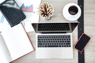Üst düzey ofis çalışma masası Kalemler, kahve fincanı, cep telefonu, dizüstü bilgisayar, tablet, çizelge ve defter grubu.