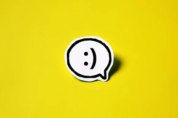 Smile speech bubble on white paper isolated on yellow paper background with drop shadow. COPY SPACE.