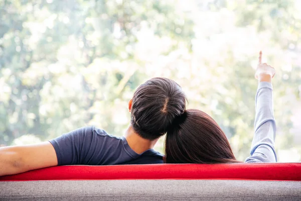 Back view of Lovely Couple sitting feeling relax and comfortable on red sofa with Green Outdoor Park View. Holiday. COPY SPACE.