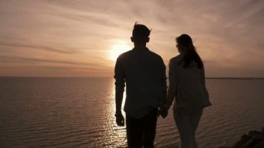 Genç adam ve kız tepelik deniz kıyısı mutlu ellerinde şiirsel bir Karadeniz sahilde duran ve harika bir gün batımı yaz aylarında pitoresk güneş yolda bakarak çok hoş bir genç çift görünümünü geri yaz aylarında tutmak