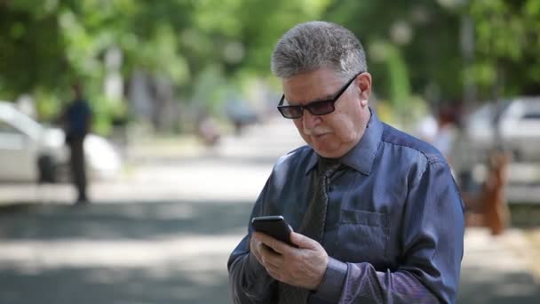 Senior Man Kijkt Naar Zijn Mobiele Raakt Het Scherm Een — Stockvideo