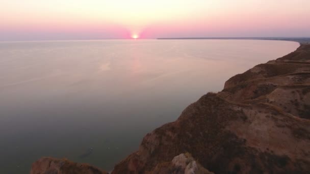 夏季日落时分在黑海海岸升起的太阳的空中拍摄一只鸟的眼睛拍摄灿烂的日落与加冕太阳在丘陵黑海沿岸的玫瑰色和紫色的水夏季 — 图库视频影像