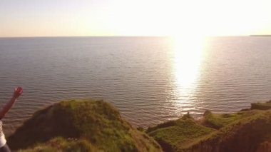 Komik kadın Karadeniz sahilinde günbatımında yaz hava mutlu bir kadın tavada, Karadeniz dikenli tepede duran ve yaz aylarında altın güneş yol zevk süre eller yükselterek pareo ile ayakta eller yükseltir