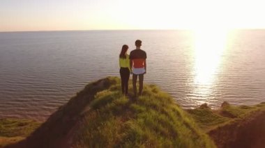 Hava güzel bir çiftin tepelik bir Karadeniz kıyısında Günbatımı muhteşem bir kuş bakışı bir tepe üzerinde duran ve yaz aylarında gün batımında parlayan güneş yol, Karadeniz zevk genç bir aile ayakta