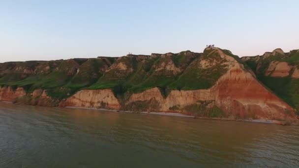 空中拍摄的丘陵黑海海岸与游客在美丽的日落鸟瞰山区黑海海岸与快乐的游客在它在夏季日落 无人机飞向他们 — 图库视频影像