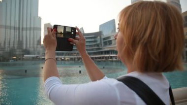 Sarışın kadın yaz profil sarışın bir kadının Buj Khalifa, dünyanın en yüksek binası çekim güneşli bir günde Dubai Uluslararası Dubai Kongre ve Sergi Sarayı fotoğraf alır. Dev bir dikit gökyüzü yaz aylarında piercing gibi görünüyor.