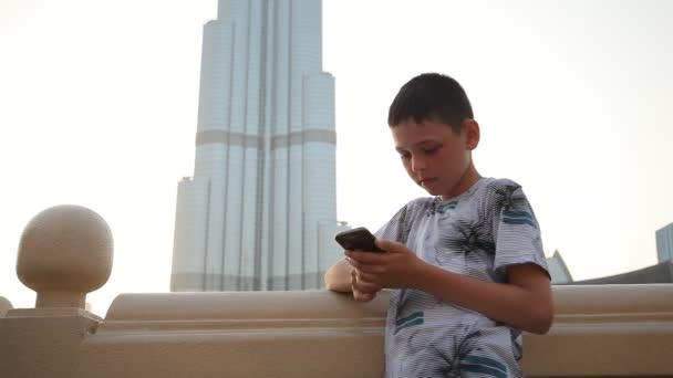 Menino Pequeno Com Smartphone Baleado Com Burj Khalifa Atrás Dele — Vídeo de Stock