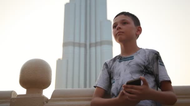 Kleiner Junge Der Auf Einem Kai Mit Dem Burj Khalifa — Stockvideo