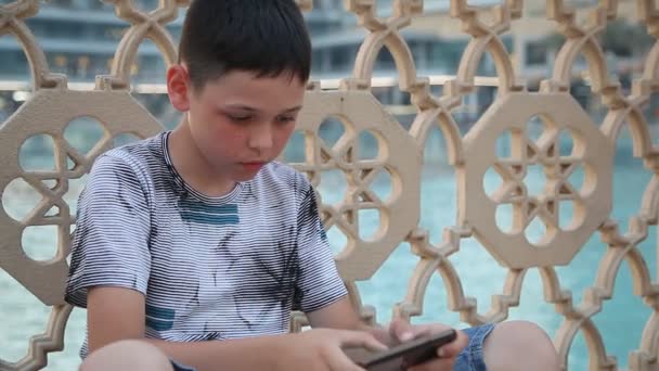 Liten Pojke Sitter Pool Och Spelar Ett Spel Sin Smartphone — Stockvideo