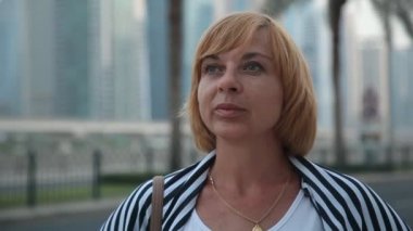 Onun husnband karayolu ile Dubai bir beyaz T-shirt, kot pantolon ve güneşli bir günde koca otoyol Dubai de bekleyen çizgili bir pelerin güzel bir kadında etkileyici bir manzara içinde gökdelenler, zarif kadın bekler