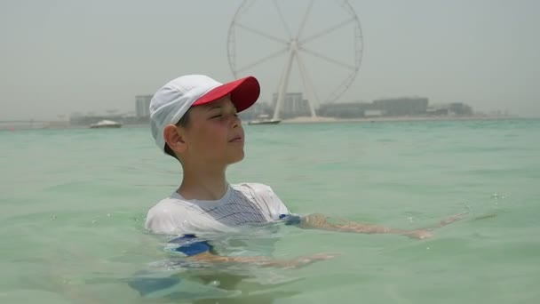 Menino Pequeno Relaxa Águas Marinhas Com Roda Gigante Fundo Dubai — Vídeo de Stock