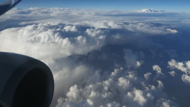 空中拍摄的白色和蓬松的云从飞机的窗口一个令人惊叹的看法从飞机窗口与看到的发动机管和雪的地幔看云在晴朗的一天夏天 — 图库视频影像