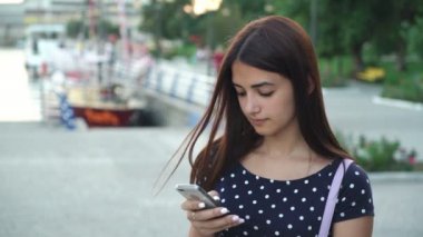 Şık kız manifatura ve yaz aylarında nehir ona telefon internette tarama bir benekli ihale genç bir kadın portresi elbise manifatura onun Smartphone ile Yatlar Port nehir iskele üzerinde yaz aylarında gün batımında
