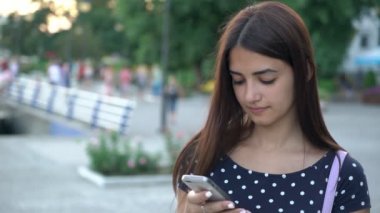 Akıllı kız gülümsüyor ve yaz aylarında nehir ona telefon internette tarama bir benekli şık genç bir kadın portresi elbise manifatura onun akıllı bir nehir iskele Ukraynalı bir bağlantı noktası üzerinde yaz aylarında gün batımında
