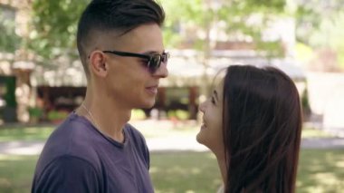 Mutlu bir adam ve sevgilisi konuşuyor ve yaz ayakta, gülümseyen, gülen ve yaz aylarında güneşli park sokakta gelecek için planlarını alışverişi aşık genç bir mutlu aile profili bir arka sokakta gülümseyen. 
