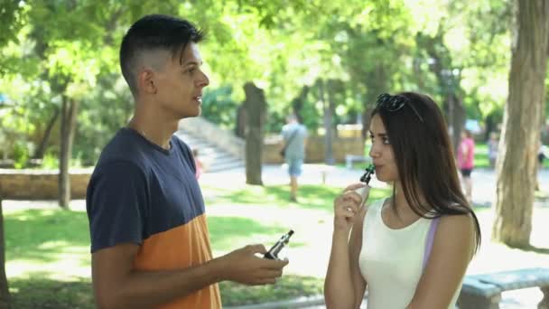 年轻人与他的女朋友在绿色公园胡同简介一个时髦的男人短发和他美丽的女朋友长头发在白色礼服站立和谈话愉快 — 图库视频影像
