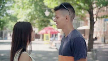 Genç adam ve kız arkadaşı sohbet ve yaz profil ayakta, gülümseyen ve onların duygu ve duygu yeşil park sokakta yazında söz aşık genç bir mutlu çiftin bir park sokakta gülümseyen. 