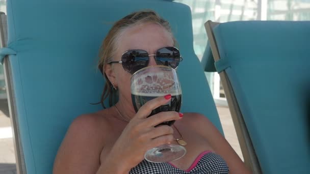 Blond Woman Sunglasses Drinks Beer Sitting Sunbed Pool Slo Optimistic — Stock Video