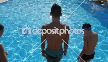 Üç erkek ayak önce slo-mo gök mavisi sularda yüzme havuzuyla atlama üç sportif erkek çocuk havuzu celeste ile atlama etkileyici bir manzara slo-mo Güneşli ışınları altında Köpüklü sular