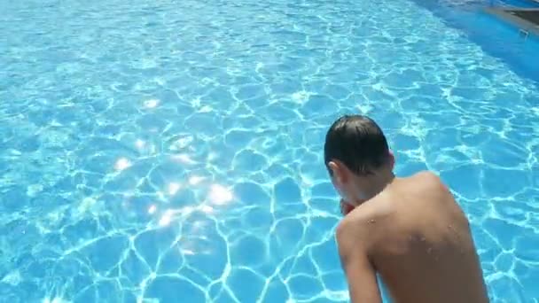 Lycklig Pojke Hoppar Fötter Först Och Snurrar Pool Med Glittrande — Stockvideo