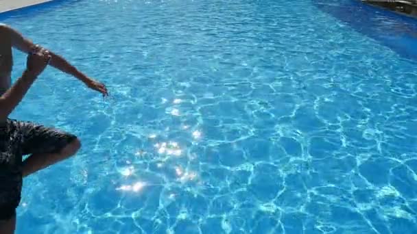 两个小男孩跳脚首先在游泳池与蓝色的水在斯洛伐克 莫一个欢快的看法 两个运动的男孩在长短裤跳脚第一高兴地进入与蔚水缓慢运动的划池 — 图库视频影像
