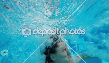 Genç kız bir yüzme havuzu ve komik görünüyor yavaş çekimde atlama havuzu ve su altında atış içinde genç bir kadın özgün bir görünümü sualtı atlar. O kadar görünüyor çok kabarcıklar korkmuş ve komik slo-mo gönderir