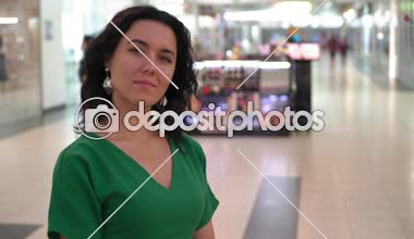 Gülümseyen ve camsı bir salonunda güzel bir kadın portresi ile gülümseyen ve geniş salonları ile bir eğlence merkezinde duran yeşil giysili bir şık dalgalı bağsız kıl ayakta Yeşil elbiseli neşeli esmer kadın