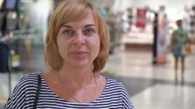 İnsanlar ile bob saç modeli bir stiped içinde neşeli sarışın bir kadın portresi ile geniş bir salonda duran ve sonsuza dek mutlu insanlar hareket ile bir büyük eğlence merkezinde gülümseyen mutlu sarışın bir kadın duruyor ve gülümseyerek elbise