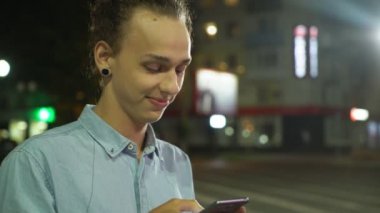 Gülümseyen ve sonbahar gece sokak derin bir kız arkadaşı arayan onun smartphone üzerinde net sörf bir topuz saç kesimi ile sonbahar profil mutlu bir genç adamın bir sokakta onun telefon ayakta net tarama şık adam