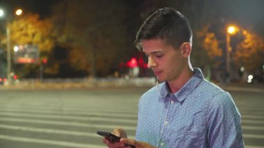 Sportif adam net sörf ve gece profil müzik ve akıllı telefonunu duran bir zebra geçiş, sonbahar gece internette tarama akıllı bir brunet insanın bir zebra kapısı ayakta