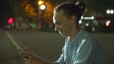 Neşeli adam mutlu onun smartphone üzerinde net tarama ve sonbaharda derin geceleri sokak bir şehirde bilgi isteyen topuz saç kesimi ile bir şehirde sonbahar profil gülünecek bir gencin sokak gülerek yaptığı telefon net sörf