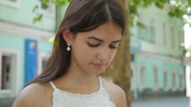 Sevimli genç güzellik yaz uzun bağsız kıl onun smartphone net açık havada ağır çekimde yaz aylarında güneşli bir tarama ile güzel bir genç kadının slo-mo profilde bir sokakta telefonunda bilgi arayan