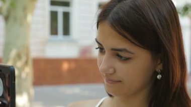Romantik genç güzellik net bir sokakta telefonunda slo-mo profil çekici bir genç kadın, yaz aylarında uzun bağsız kıl onun smartphone üzerinde açık havada ağır çekimde yaz aylarında güneşli bir günde internette sörf ile sörf