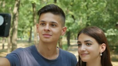 Romantik adam yavaş hareket şaşırtıcı görünümü yakın duygusal olarak yeşil bir ormanda gülümseyen onun tatlı brunet kızla bir selfie alarak bir ilham gencin ormandaki güzel bir kız arkadaşı ile selfie alıyor      