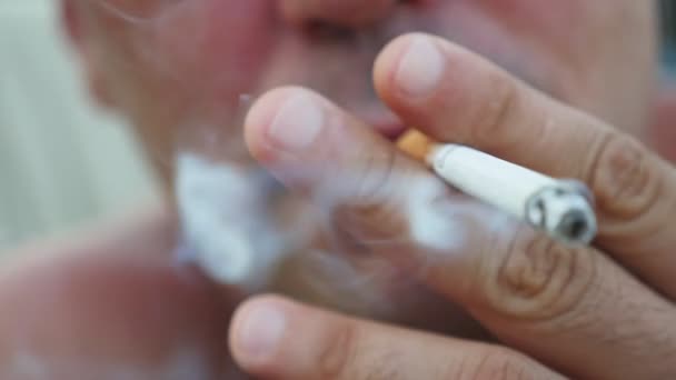 Un homme calme fume une cigarette et respire de la fumée dense en été au ralenti Photo macro d'une cigarette allumée avec de la cendre grise dans la bouche d'un homme tranquille qui respire un jet de fumée épaisse en été au ralenti 