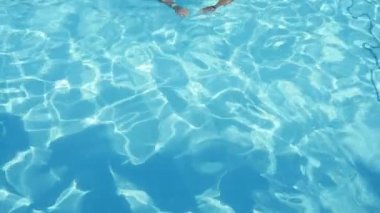 Sportif brunet adam yüzme kurbağalama celeste havuzu yavaş hareket breastsroke bir ışık mavi yüzme havuzda bir kameraman için açık havada yaz yavaş yüzme bir brunet gencin etkileyici görünüm