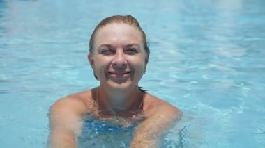 Mutlu kadın ayakta ve yaz aylarında yüzme, gülümseyen ve mutlu bir şekilde yavaş yaz aylarında yüzme havuzunda eğlenceli bikini neşeli sarışın bir kadın portresi slo-mo içinde bir yüzme havuzunda hayattan zevk,