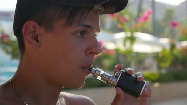 Jovem Está Fumando Cigarro Eletrônico Livre Parque Ensolarado Câmera Lenta — Vídeo de Stock