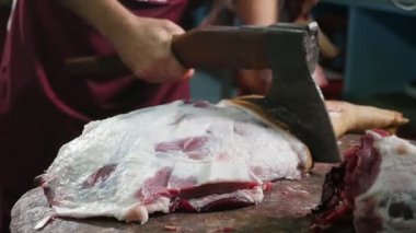 Kasap'ın yavaş hareket çarpıcı closeup kesme ve bir kasaplık yavaş hareket içinde ahşap bir masa üzerinde domuz etli domuz yağı, kaburga ve ayaklar doğrama kasap'ın elinde bir balta kullanarak ayaklı haşıl domuz leşini eller