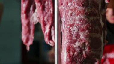 Domuz eti, Dana ve sığır eti hangling çiğ et parçaları üst üste büyük gıda ambar içinde büyük kanca asılı bir büyük dondurucu şaşılacak closeup içinde uzun şeritler. Bir kasap zemin içinde görülür.