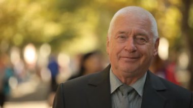 Mutlu ihtiyar bir picturesue parkta sonbahar siyah takım elbise ve kravat ayakta ve harika bir altın parkta sonbaharda gülümseyen bir şık beyaz saçlı adam neşeli görünümünü ayakta bir koyu takım elbise