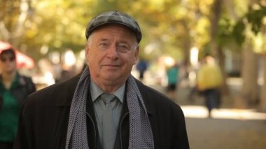 İyimser beyaz saçlı adam bir düz kapak, kravat ve ceket ayakta şık bir ihtiyar bir ekose düz kapak, takım elbise, kravat ve uzun ceket altın bir parkta sonbaharda gülümseyen güzel park Bokeh portresi