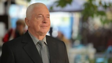 İyimser bilge adam ayakta ve saygın bir üst düzey adam ayakta ve eşi bir sokakta sonbaharda beklenirken gülümseyen bir siyah takım elbise içinde onun karısı açık neşeli görünümü için bekleyen bir takım elbise içinde