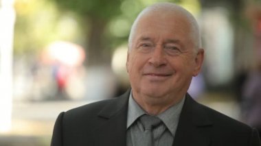 Bir yeşil sokak sonbahar neşeli bokeh portre siyah elbiseli duran ve sonsuza dek mutlu bir yeşil sonbaharda sokak gülümseyen bir expirienced yaşlı adamın gülümseyen iş elbiseli iyimser bilge adam