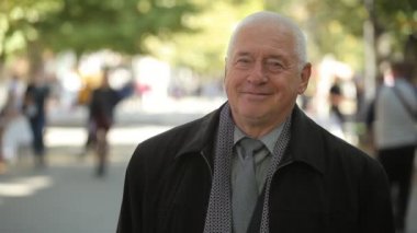 İyimser akıllı yaşlı adam bir yeşil sokak temiz kat, eşarp, gömlek ve kravat mutlu bir yeşil sonbaharda sokak gülümseyen bir beyaz saçlı adamın sonbahar neşeli portre gülümseyen.    