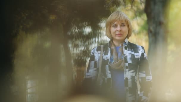 Bissige Blonde Frau Steht Und Lächelt Fröhlich Einem Dunklen Park — Stockvideo